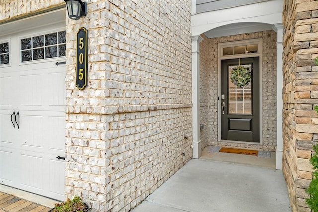 entrance to property featuring a garage and stone siding