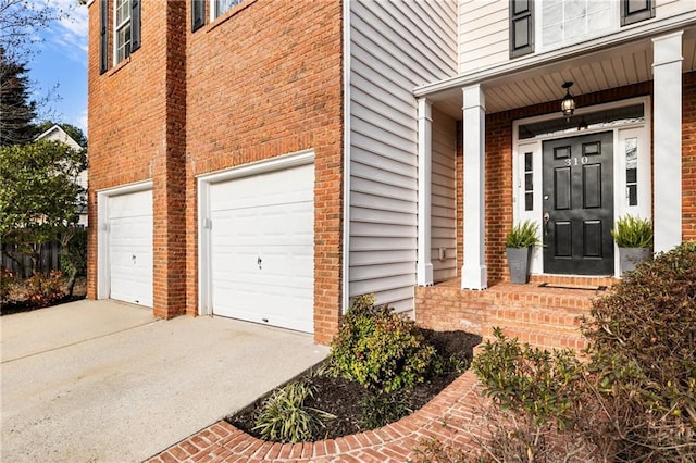 view of exterior entry featuring a garage, concrete driveway, and brick siding