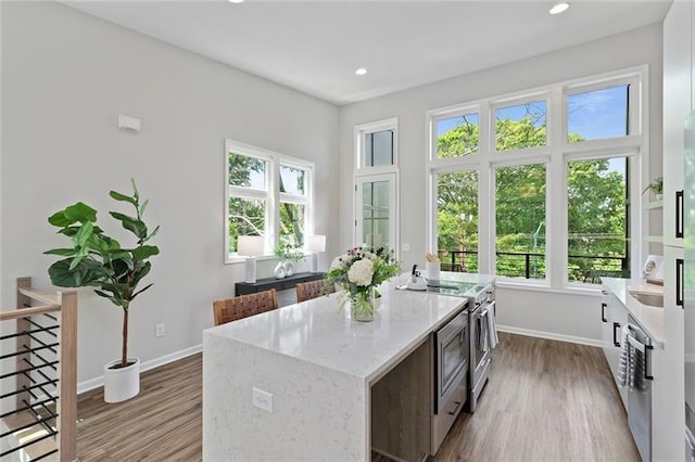 kitchen with light stone countertops, electric range, a kitchen island, and light hardwood / wood-style floors