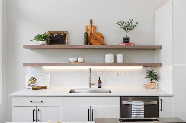 bar with tasteful backsplash, white cabinetry, sink, and dishwasher