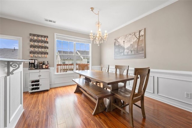 3542 Chattahoochee Summit Ln SE, Atlanta, GA 30339 - dining room with crown molding, a chandelier, wood finished floors, a decorative wall, and a dry bar