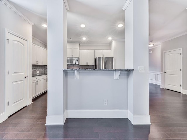 212 Torch Dr, Acworth, GA 30102 - kitchen with stainless steel appliances, ornamental molding, dark stone counters, a breakfast bar area, and recessed lighting