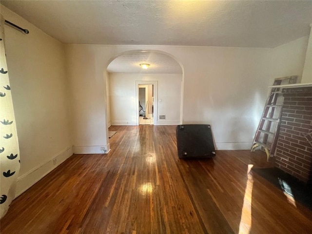 empty room with a textured ceiling and dark hardwood / wood-style floors