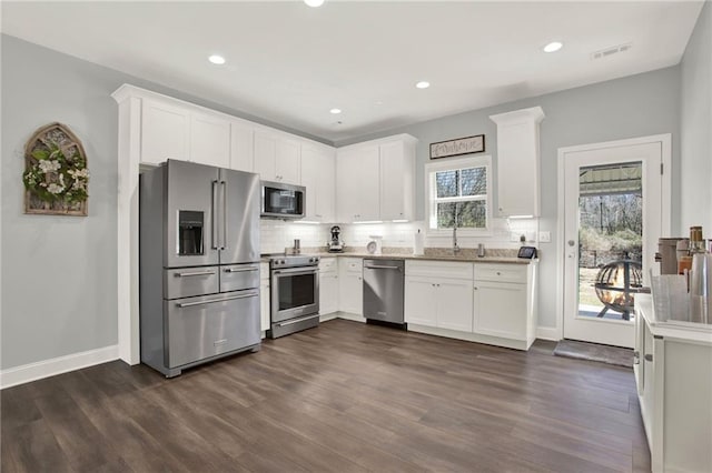 kitchen featuring appliances with stainless steel finishes, visible vents, dark wood finished floors, and tasteful backsplash