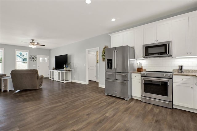 kitchen featuring white cabinets, stainless steel appliances, backsplash, and open floor plan