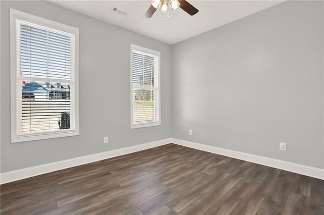 unfurnished room featuring dark wood finished floors, a ceiling fan, and baseboards