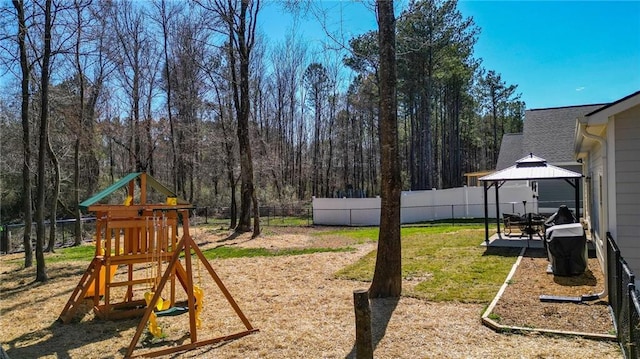 view of yard featuring a view of trees, fence, a playground, and a gazebo