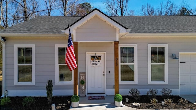 entrance to property featuring a shingled roof and an attached garage