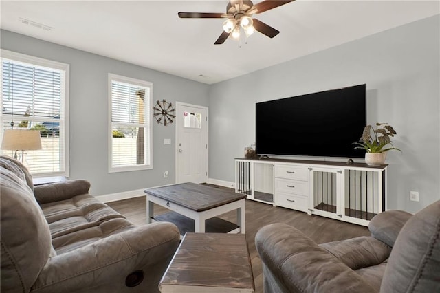 living area featuring dark wood-style floors, baseboards, visible vents, and a ceiling fan