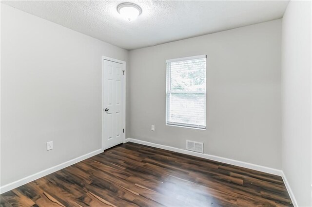 spare room with dark hardwood / wood-style floors and a textured ceiling