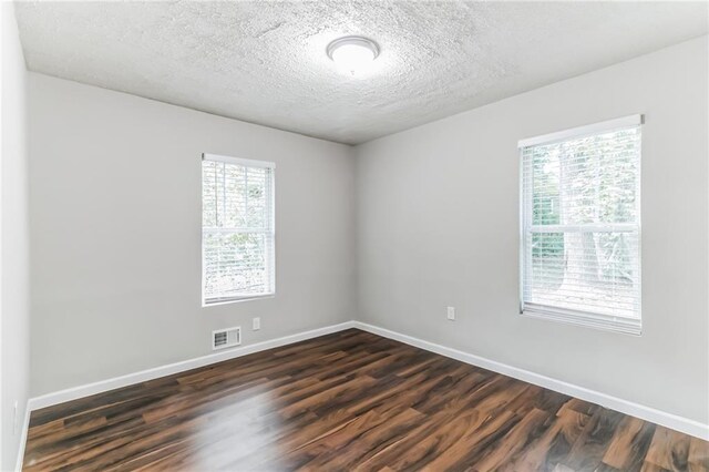 empty room with dark hardwood / wood-style flooring and a textured ceiling