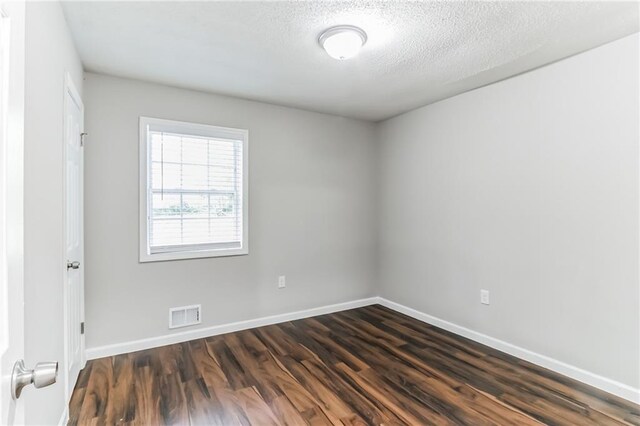 spare room featuring dark hardwood / wood-style floors and a textured ceiling