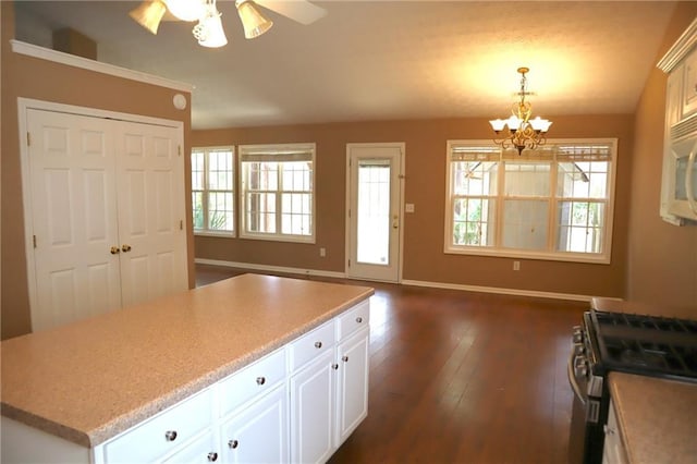 kitchen featuring gas stove, baseboards, dark wood finished floors, and white cabinetry