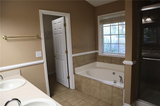 full bath featuring a sink, a garden tub, double vanity, and tile patterned floors