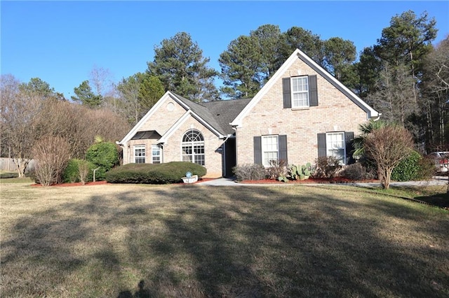 traditional home featuring a front yard and brick siding