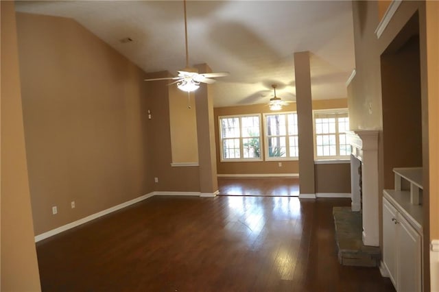 unfurnished living room with baseboards, lofted ceiling, a fireplace with raised hearth, and dark wood-style flooring