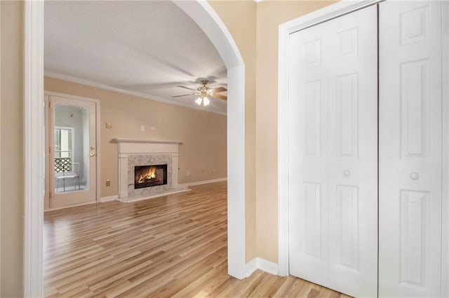 205 Peachtree Forest Ter, Peachtree Corners, GA 30092 - unfurnished living room featuring ceiling fan, light wood-type flooring, crown molding, arched walkways, and a high end fireplace