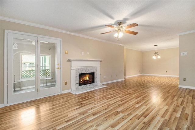 205 Peachtree Forest Ter, Peachtree Corners, GA 30092 - unfurnished living room featuring a high end fireplace, light wood-style flooring, a ceiling fan, a chandelier, and crown molding