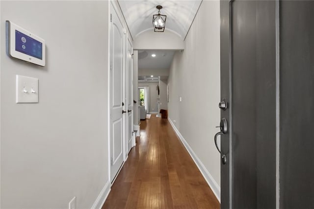 hallway with vaulted ceiling, dark wood-style floors, and baseboards