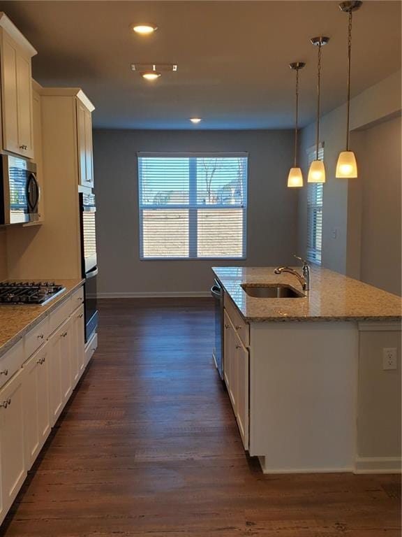 kitchen featuring white cabinets, decorative light fixtures, a kitchen island with sink, stainless steel appliances, and dark hardwood / wood-style floors