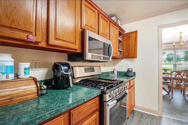 3514 Blackberry Ln SE, Conyers, GA 30094 - kitchen featuring stainless steel appliances, wood finished floors, a chandelier, crown molding, and brown cabinets