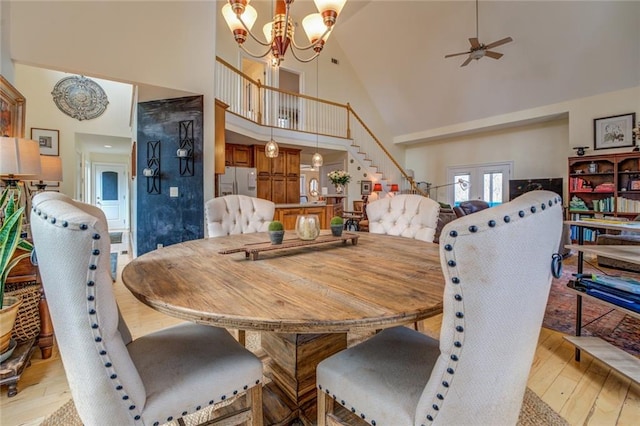 dining area featuring french doors, high vaulted ceiling, light wood-type flooring, and ceiling fan with notable chandelier