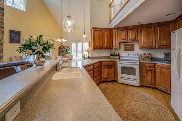 kitchen with white appliances, sink, high vaulted ceiling, an inviting chandelier, and light wood-type flooring