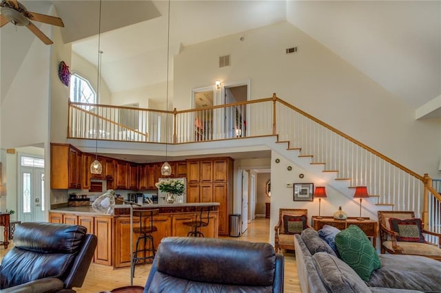 living room featuring high vaulted ceiling, ceiling fan, and light hardwood / wood-style flooring