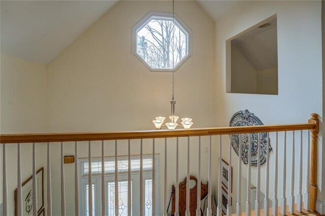 hall with hardwood / wood-style floors, a notable chandelier, and vaulted ceiling