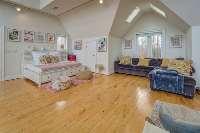 bedroom with lofted ceiling with skylight and light hardwood / wood-style flooring