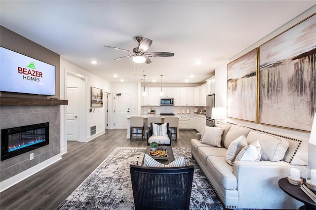 living room featuring ceiling fan, a fireplace, and dark wood-type flooring