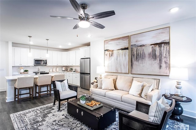 living room featuring ceiling fan, dark wood-type flooring, and sink