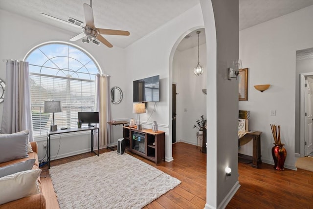 sitting room with hardwood / wood-style floors and ceiling fan with notable chandelier