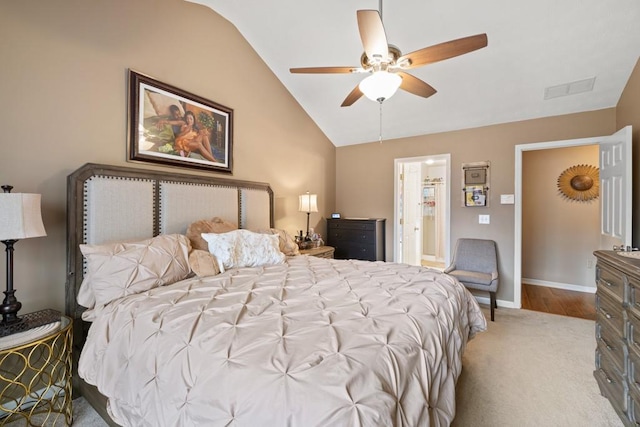 bedroom featuring vaulted ceiling, ensuite bathroom, light colored carpet, and ceiling fan