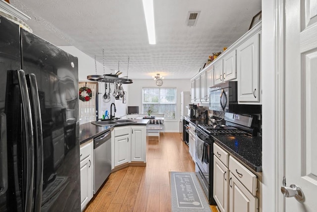 kitchen with white cabinetry, sink, light wood-type flooring, and black appliances