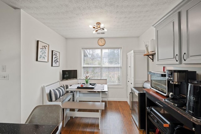 dining area featuring a notable chandelier, dark wood-type flooring, wine cooler, and a textured ceiling