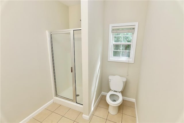 bathroom featuring toilet, a shower with door, and tile patterned floors