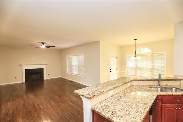 kitchen with sink, hanging light fixtures, light stone countertops, and dark wood-type flooring