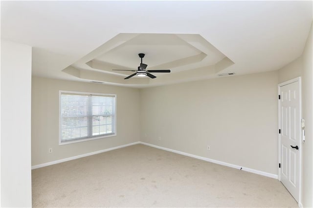 spare room with light colored carpet, a raised ceiling, and ceiling fan