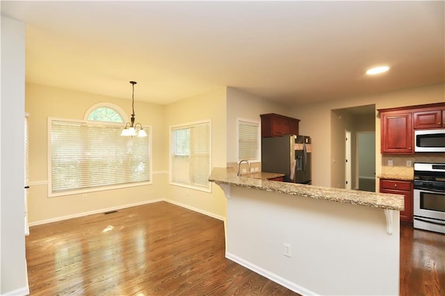 kitchen with black fridge, a kitchen bar, kitchen peninsula, decorative backsplash, and range