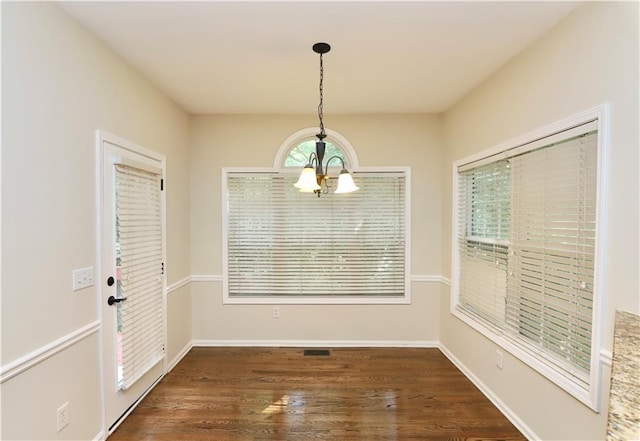 unfurnished dining area featuring a chandelier and dark hardwood / wood-style floors