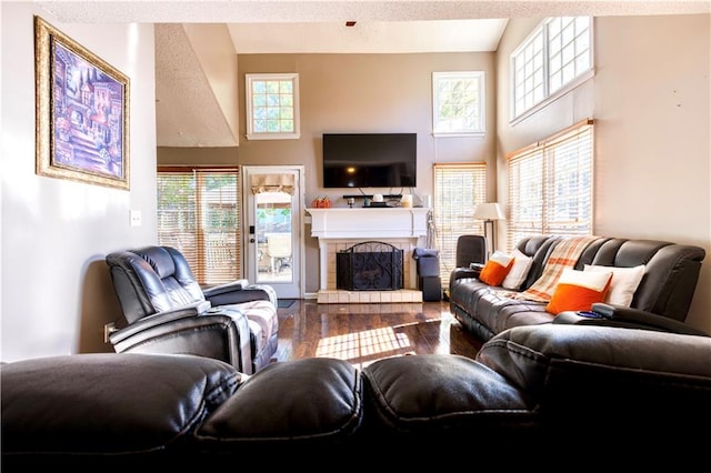 living room featuring a tile fireplace, wood-type flooring, and a textured ceiling