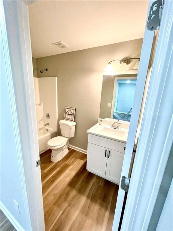 full bathroom featuring washtub / shower combination, wood-type flooring, toilet, and vanity