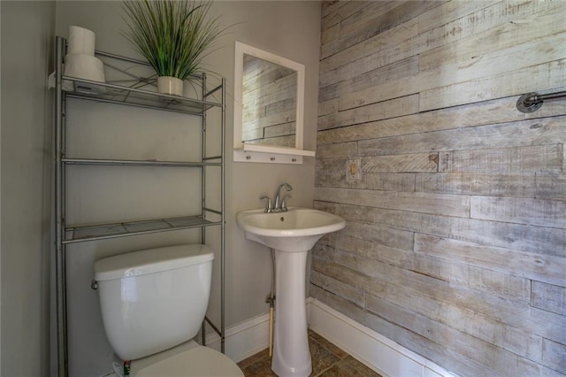 bathroom featuring toilet and wood walls