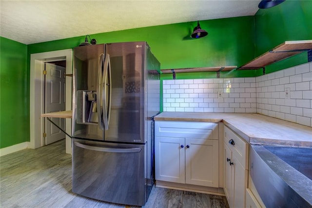 kitchen featuring light wood-type flooring, butcher block countertops, backsplash, white cabinetry, and stainless steel fridge with ice dispenser