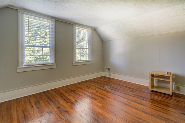 bonus room featuring lofted ceiling, a textured ceiling, and dark wood-type flooring