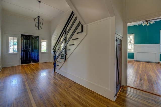 foyer with hardwood / wood-style floors and ceiling fan with notable chandelier