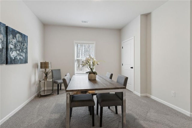 carpeted dining space with baseboards and visible vents