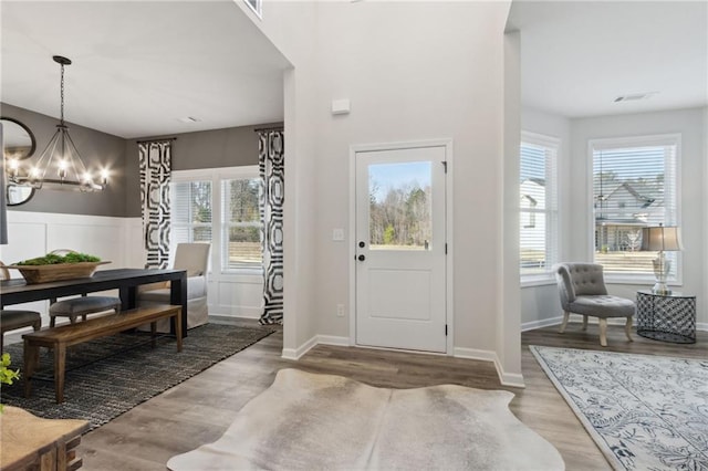 foyer featuring visible vents, a wealth of natural light, wood finished floors, and a notable chandelier
