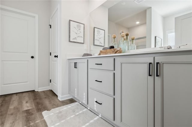 full bath featuring double vanity, baseboards, and wood finished floors